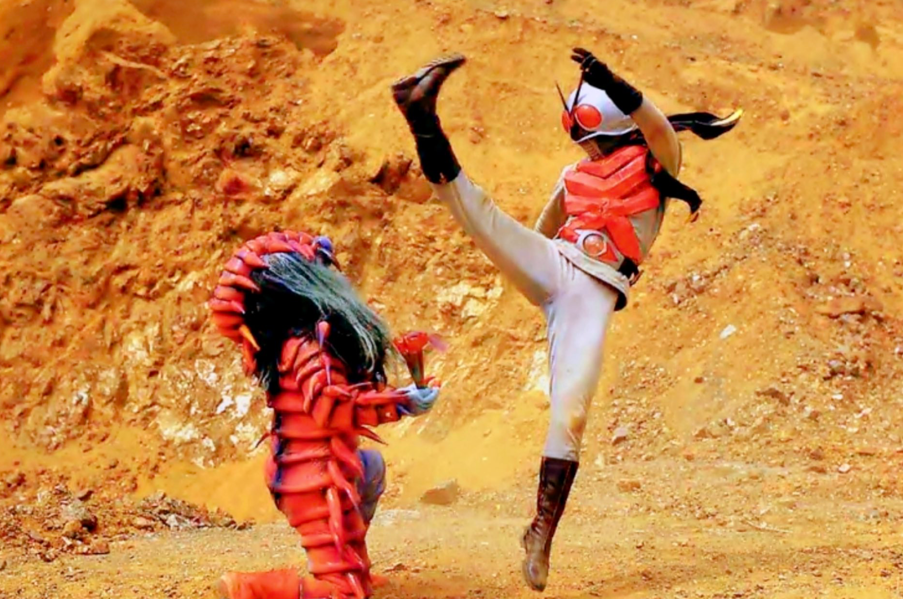 Kamen Rider desfere um golpe voador contra um monstro